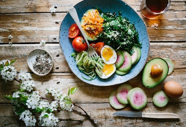 Pocherat ägg med grönsaker och tomater på blå tallrik